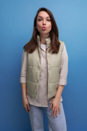pretty european brunette young woman in vest and shirt on studio backgroundの写真素材