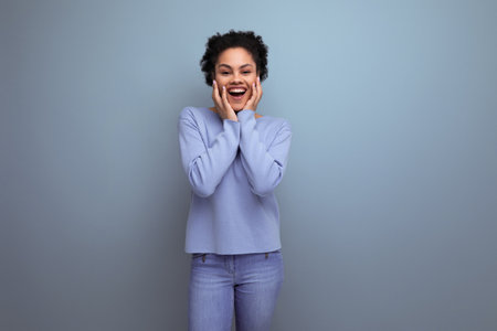 positive energetic young brunette latin lady with afro curls in stylish spring clothes on isolated...