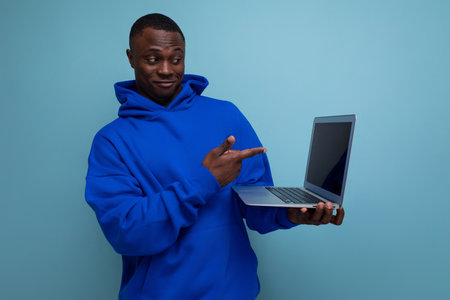 handsome successful african man young laptop user checks the work of technology on the background with copy spaceの写真素材