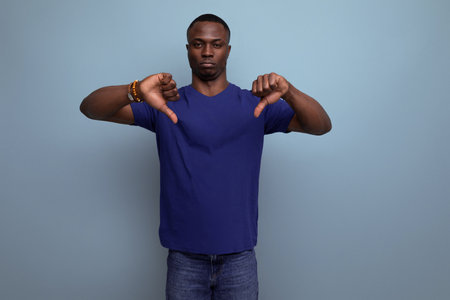 attractive 25c african guy in casual blue t-shirt showing dislikeの写真素材