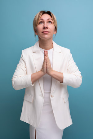 young slender female adult wearing jacket and dress prayingの写真素材