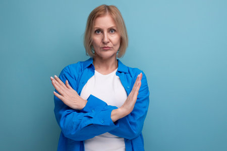 blond mature woman with arms crossed in studio background