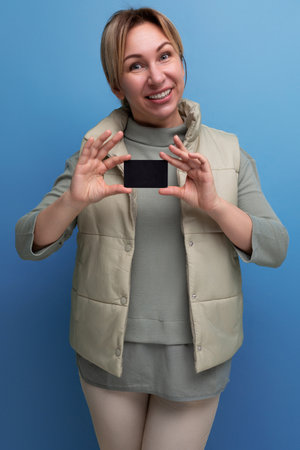 happy blond 30 year old woman in casual wear holding money card mockupの写真素材