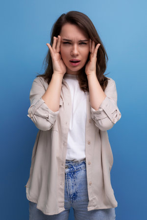 pretty young brunette female adult in casual shirt with headacheの写真素材