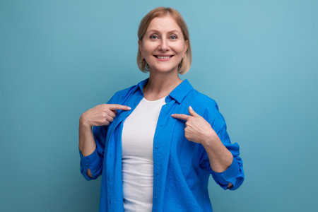 smiling genius blond middle aged woman on blue background with copyspaceの写真素材