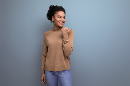 young authentic hispanic lady with afro curly hair in casual clothes posing against background with copy spaceの写真素材