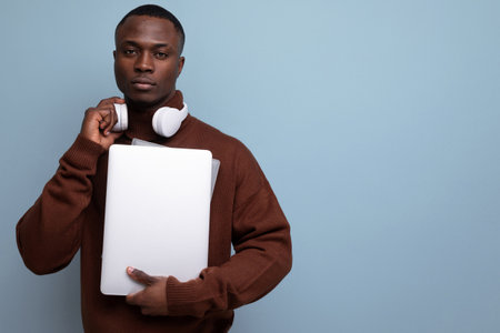 successful young african male freelancer with a laptop in his hands on the background with copy...