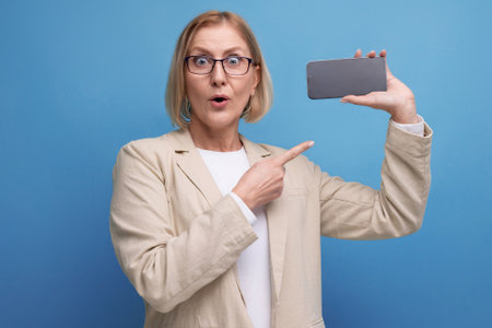 middle-aged woman with a bob hairstyle in a classic jacket holds a credit card with a mockup for shopping on a bright background with copy spaceの写真素材
