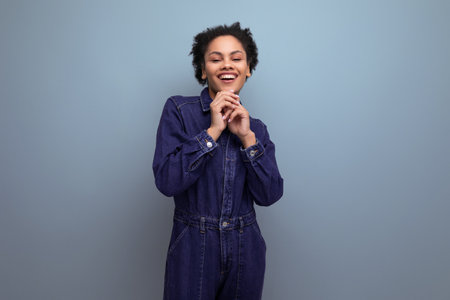 young hispanic brunette woman with fluffy curly hair posing in blue denim suitの写真素材