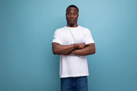 handsome young african man in white t-shirt on blue background with copy spaceの写真素材
