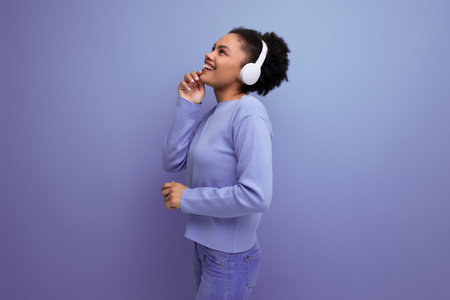 positive young afro brunette woman listening to music in wireless headphonesの写真素材