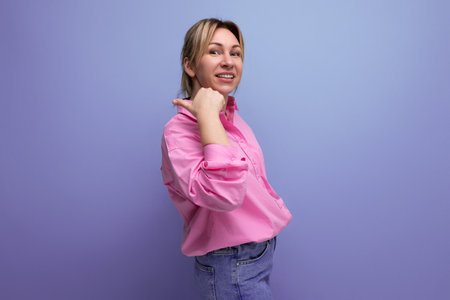 young smiling european blond office worker woman dressed in a pink shirt and jeansの写真素材