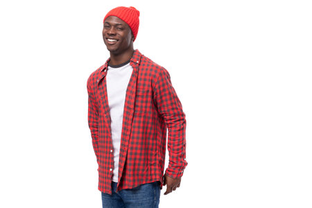 portrait of a dreamy modest 30s black american man dressed in a red shirt and cap on a white studio...