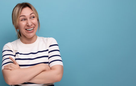 close up photo of adorable energetic happy blonde millennial woman in striped casual blouse on blue background with copy spaceの写真素材