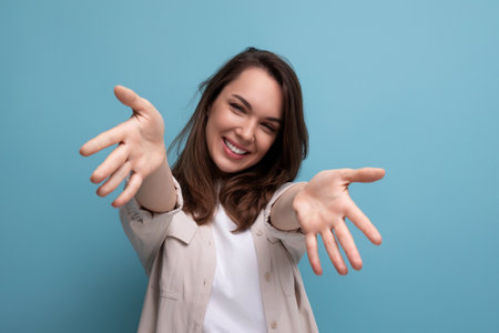 cheerful cute brunette young brunette lady dressed in a shirt and jeans sips her hands for a hugの写真素材