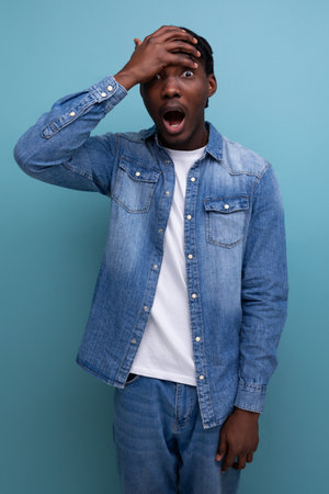 close-up portrait of a surprised shocked young stylish american guy with dreadlocks in a denim jacketの写真素材