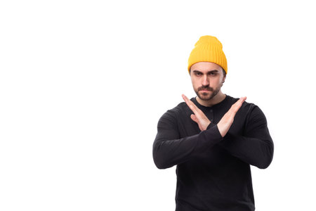 young brutal male model dressed in a black jacket and yellow hat crossed his arms