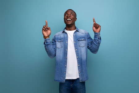 young handsome african guy in urban clothes gesturing pointing to advertising space on isolated background with copy spaceの写真素材