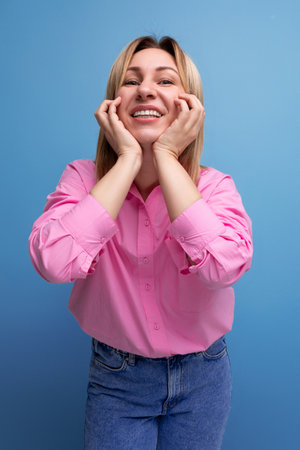young pretty blond european office worker woman with flowing hair in a pink blouse smiles sweetlyの写真素材