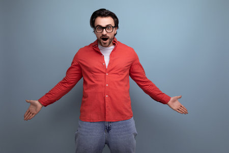 stylish surprised european 35 year old man in casual shirt throws up his hands