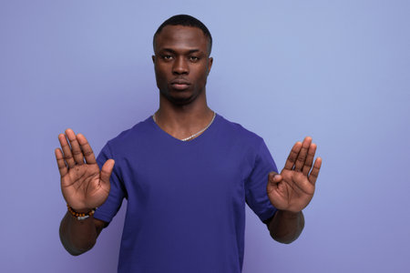 serious young african man in blue t-shirt asks to stopの写真素材