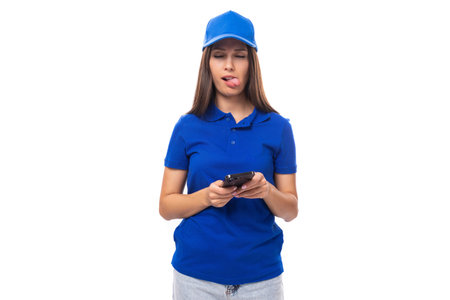 young woman promoter in a blue t-shirt and cap uses a smartphoneの写真素材