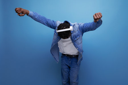energetic american man with dreadlocks in denim jacket dancing to music with headphones