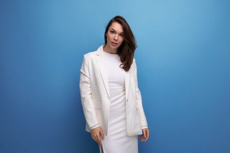 fashion business young lady in white dress and jacket posing on studio background with copyspaceの写真素材
