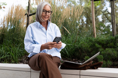 portrait of a slender gray-haired middle-aged business woman dressed in a shirt and trousers on the...