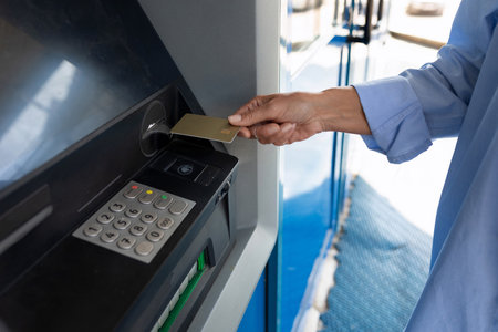 close-up of a woman inserting a bank card into an ATMの写真素材