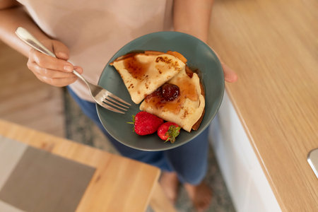 a woman serves homemade pancakes using berries and jam
