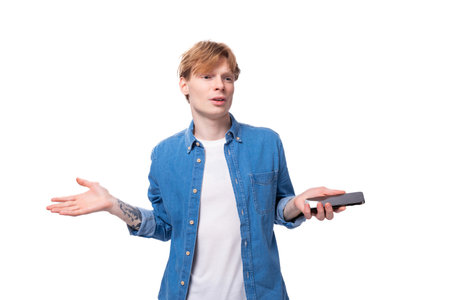 young guy with red hair in a denim shirt throws up his hands