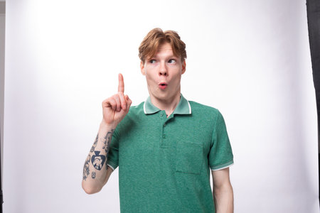 young smart caucasian man with red hair dressed in a green t-shirt is inspired by an idea on a...