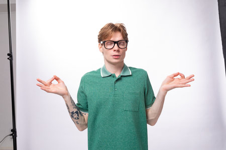young calm smart man with red hair in glasses meditatesの写真素材