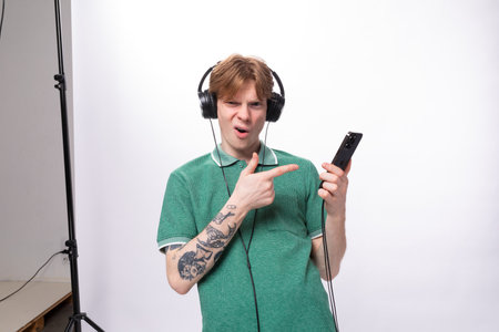 young music lover man with red hair dressed in a green T-shirt in large headphones listens to musicの写真素材