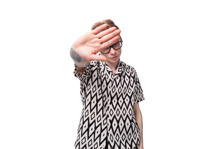 young european male student with red hair dressed in a shirt with a rhombus pattern shows a stop...