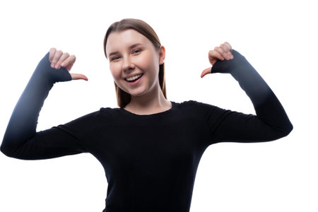 Pre-teen girl with brown hair in black clothes points her hands at herselfの写真素材