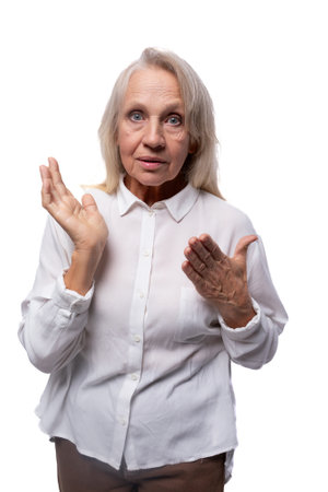 An elderly suspicious woman with gray hair looks carefully at the cameraの写真素材