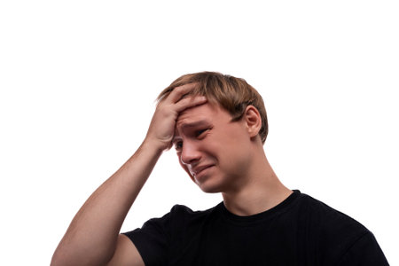 Excited teenager guy in a black T-shirt holding his head