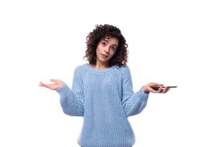 a young lady with black curly hair dressed in a light blue sweater spreads her arms and doubts on a...