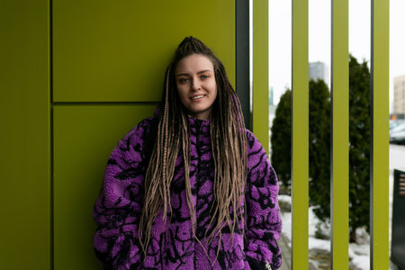 Lifestyle concept. A young pretty woman with dreadlocks and piercings stands at the entrance to a...