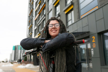 Cute young woman with dreadlocks hairstyle and bicycle in an urban environment
