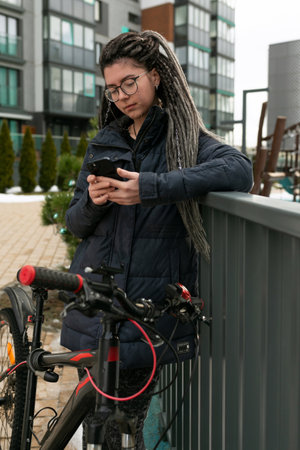 A pretty young woman with a dreadlocked hairstyle rides a bicycle and stops to restの写真素材