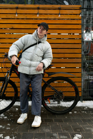 Bike rental concept. A man walks through the city in winter with a bicycle