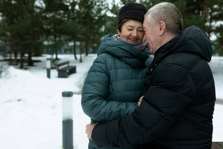 Cute mature couple experiencing love for each other while walking in the park in winterの写真素材