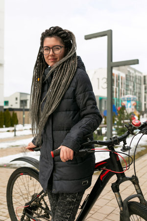 A pretty young woman with a dreadlocked hairstyle rides a rented bicycle