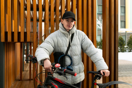 A young Caucasian man with a gray jacket and black cap rented a bicycle