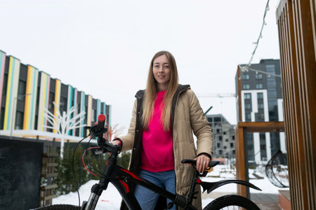 Woman Standing Next to Bike in Snowの写真素材