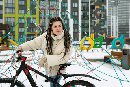 Woman Standing Next to Bike in Snowの写真素材