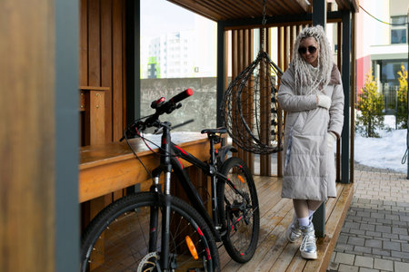 Woman Standing Next to Bike on Wooden Platformの写真素材